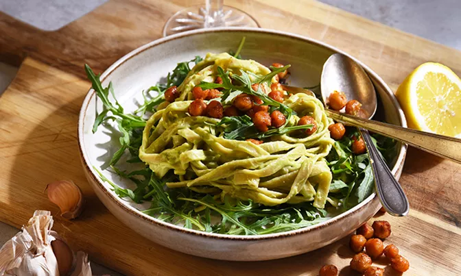 A bowl of pasta, arugula, and chickpeas.