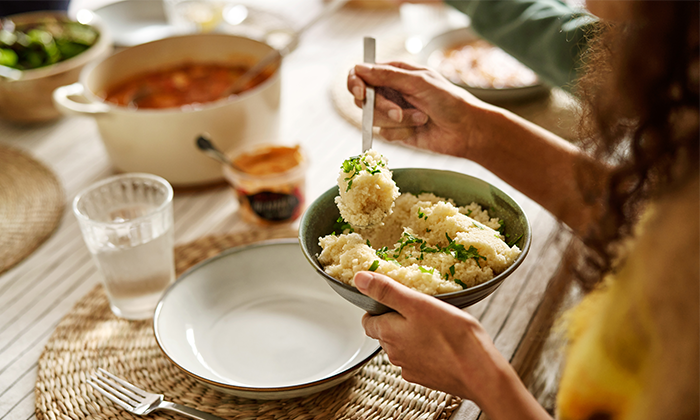 A women sitting by a table and eating coscos.